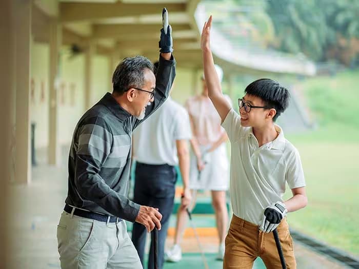 father and son high fiving on golf course
